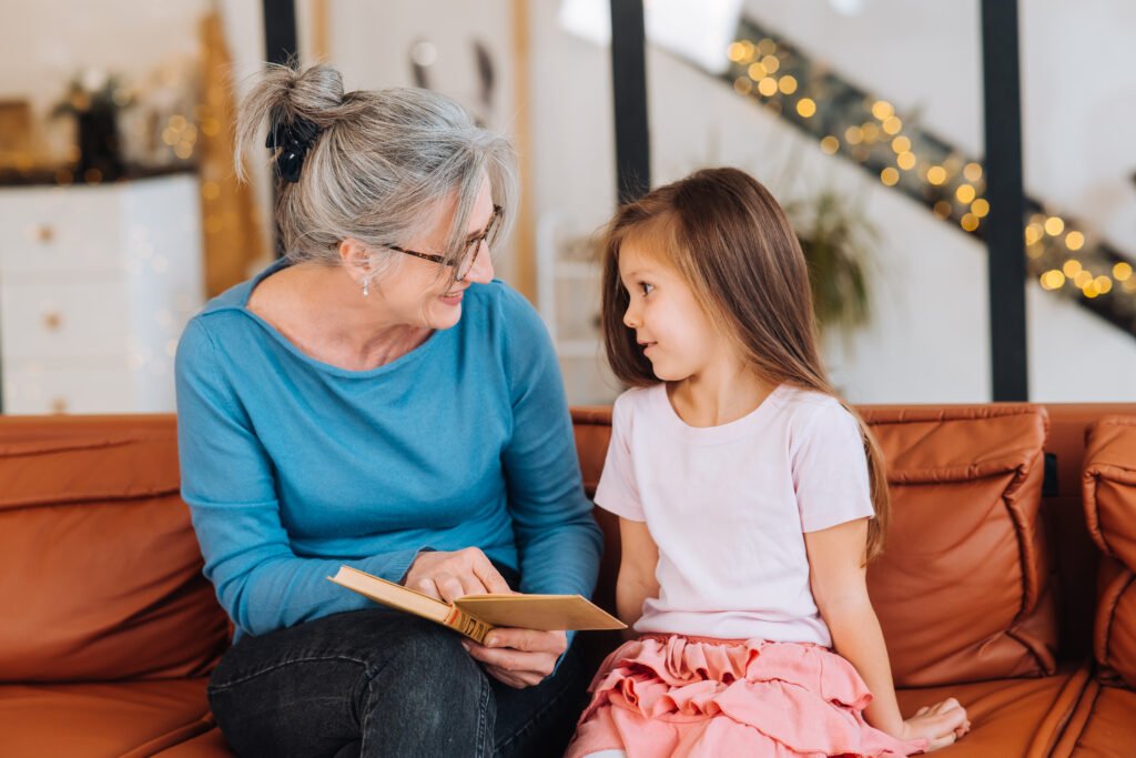 Nice elderly woman grandmother reading story to granddaughter